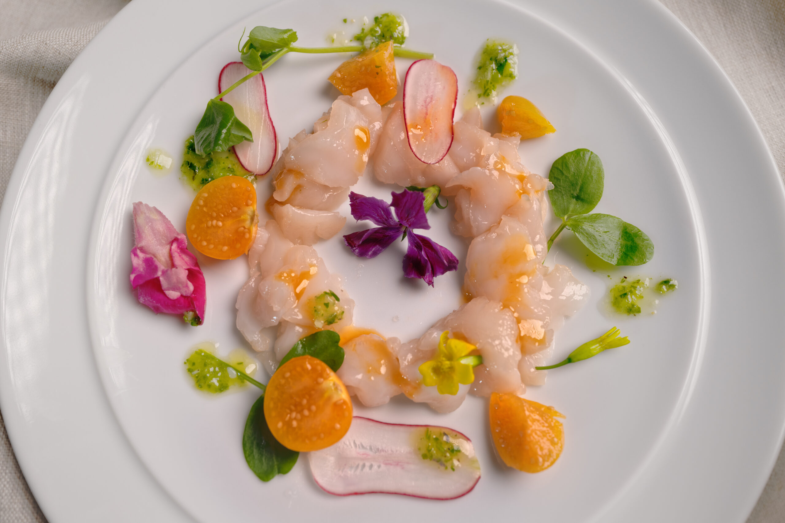 Plated Scallop Carpaccio with wild flowers.